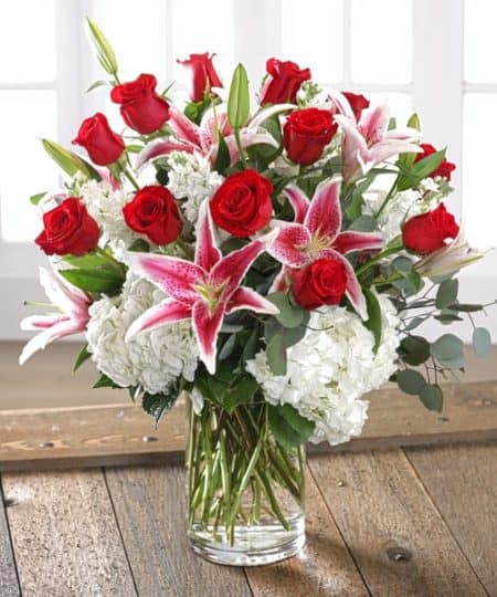 ombination garden of exclusive Ecuadorian Red Mountain Roses and Dutch garden flowers including full-bloom garden hydrangea and fragrant stargazer lilies bursting from a chic glass vase.