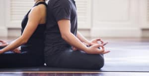 Yoga couple meditating back to back 
