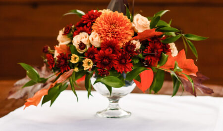 autumn floral bouquet in a pumpkin vase for Halloween. Table setting for wedding