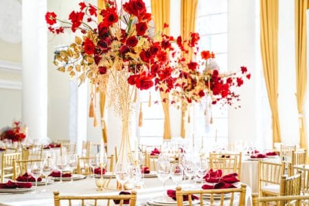 Floral arrangement, festive bouquet, table decoration for Chinese New Year party celebration in restaurant. Traditional red gold color decor. Roses,poppies,fan,candles,tassels. Chinese lunar calendar.