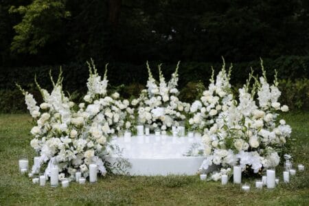 A beautiful display of white flowers surrounded by candles sets the perfect mood for a memorable outdoor event, radiating tranquility and elegance.